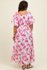 woman wearing a floral pink maxi maternity dress with puff sleeves and a smocked back, showing a baby bump