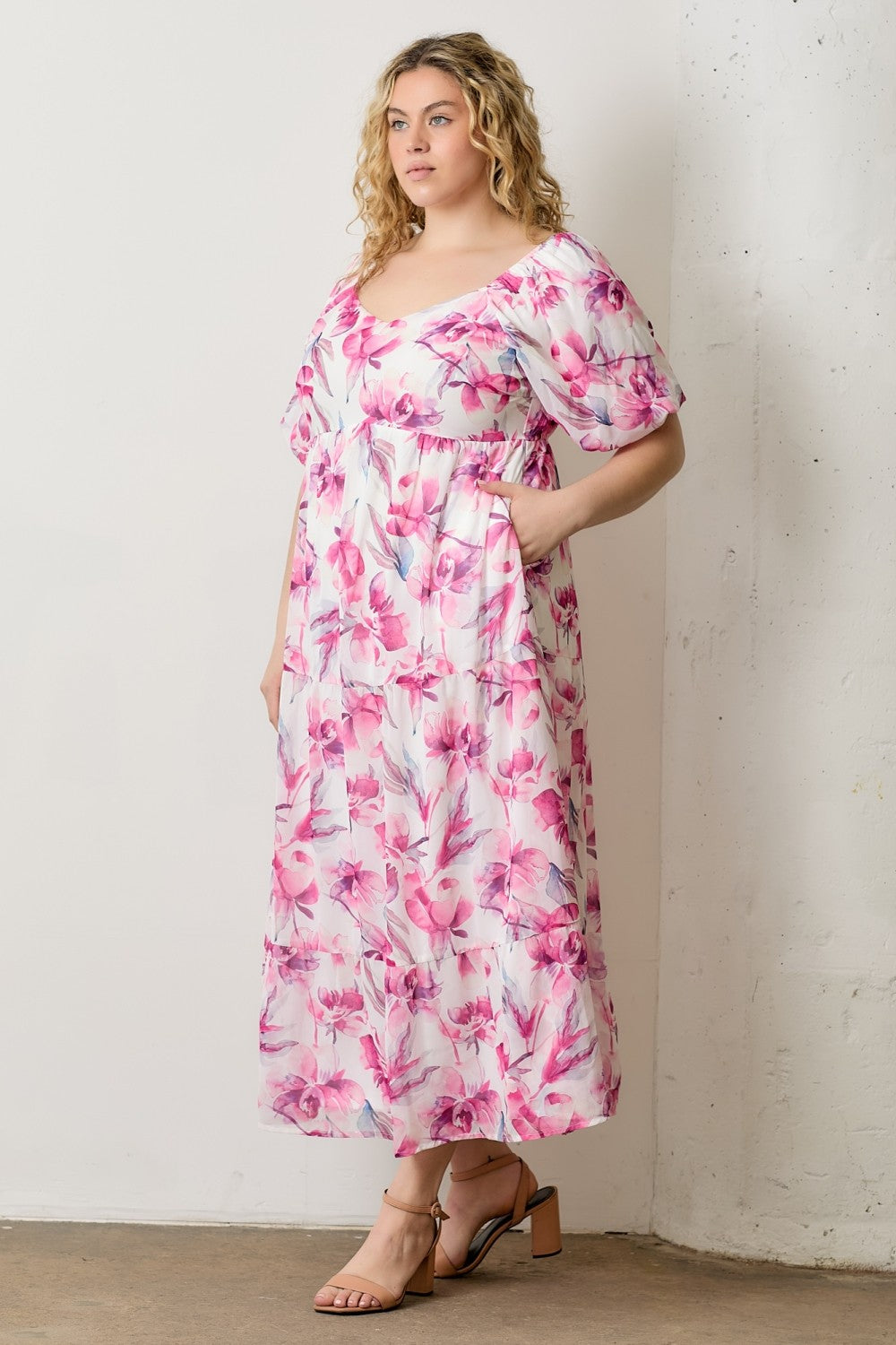 woman wearing a floral midi dress with pink and purple patterns and puff sleeves, styled with sandals