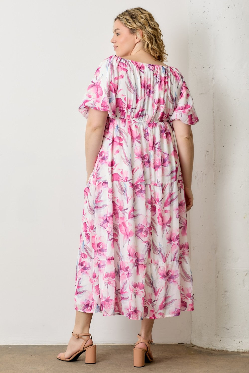 woman wearing a floral plus size maxi dress with puff sleeves and a cinched waist, seen from the back