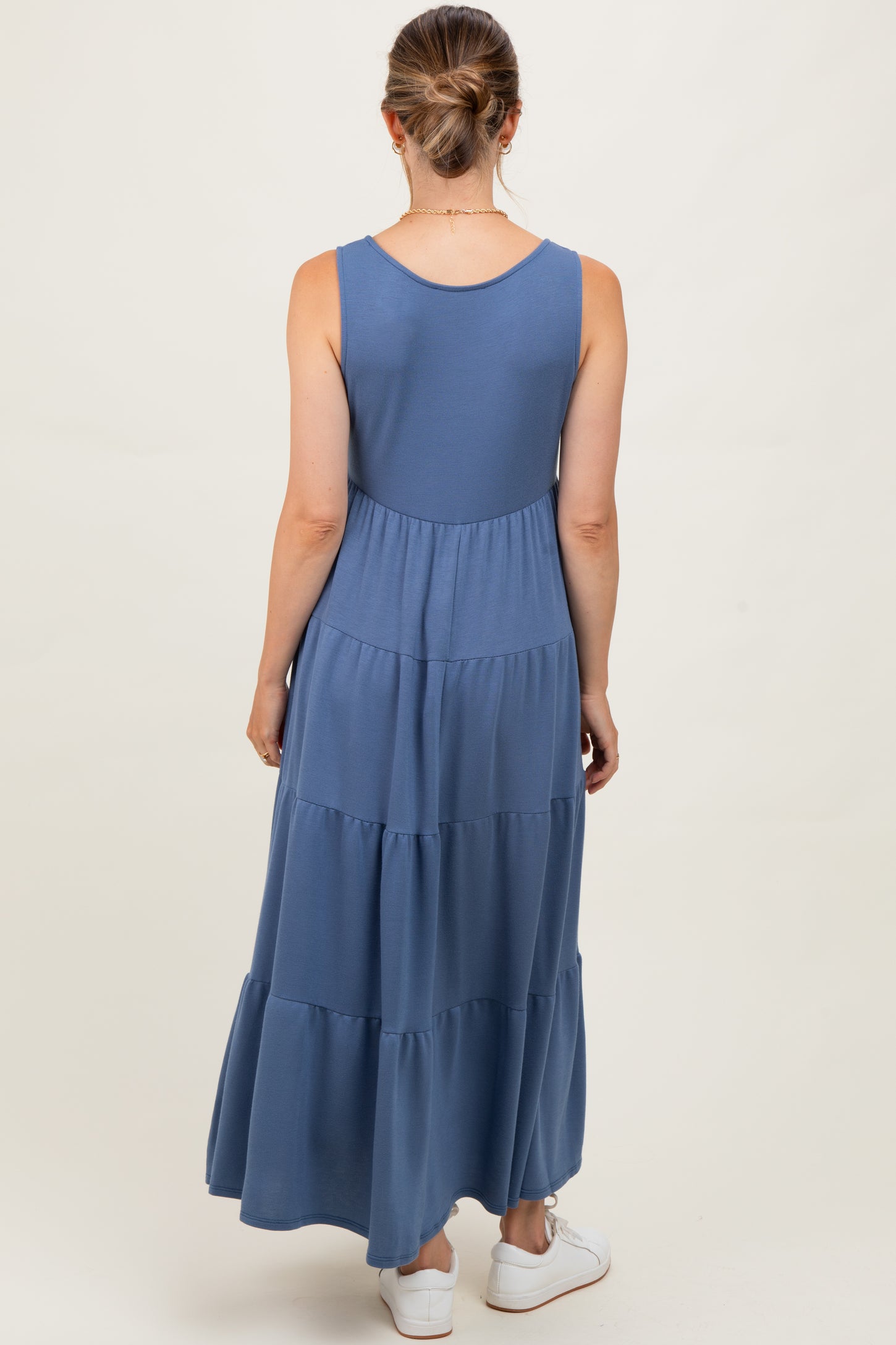 woman wearing a long blue maternity maxi dress with tiered layers, showing the back view