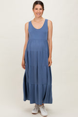 woman wearing a blue sleeveless maternity maxi dress with a flowy tiered design and a visible baby bump