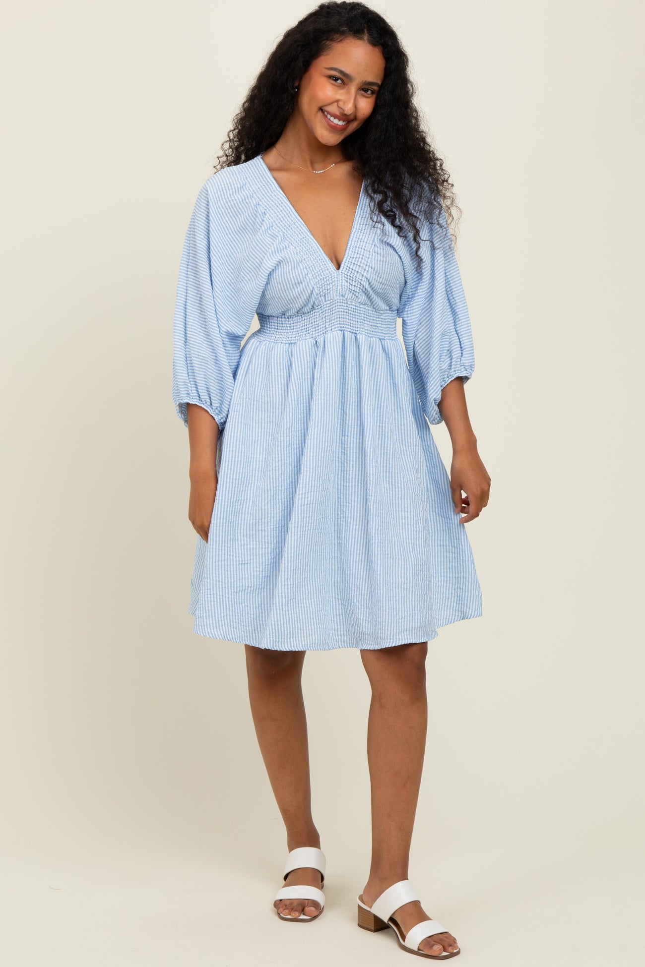 woman wearing a light blue striped short sleeve dress with a deep v-neckline and a cinched waist