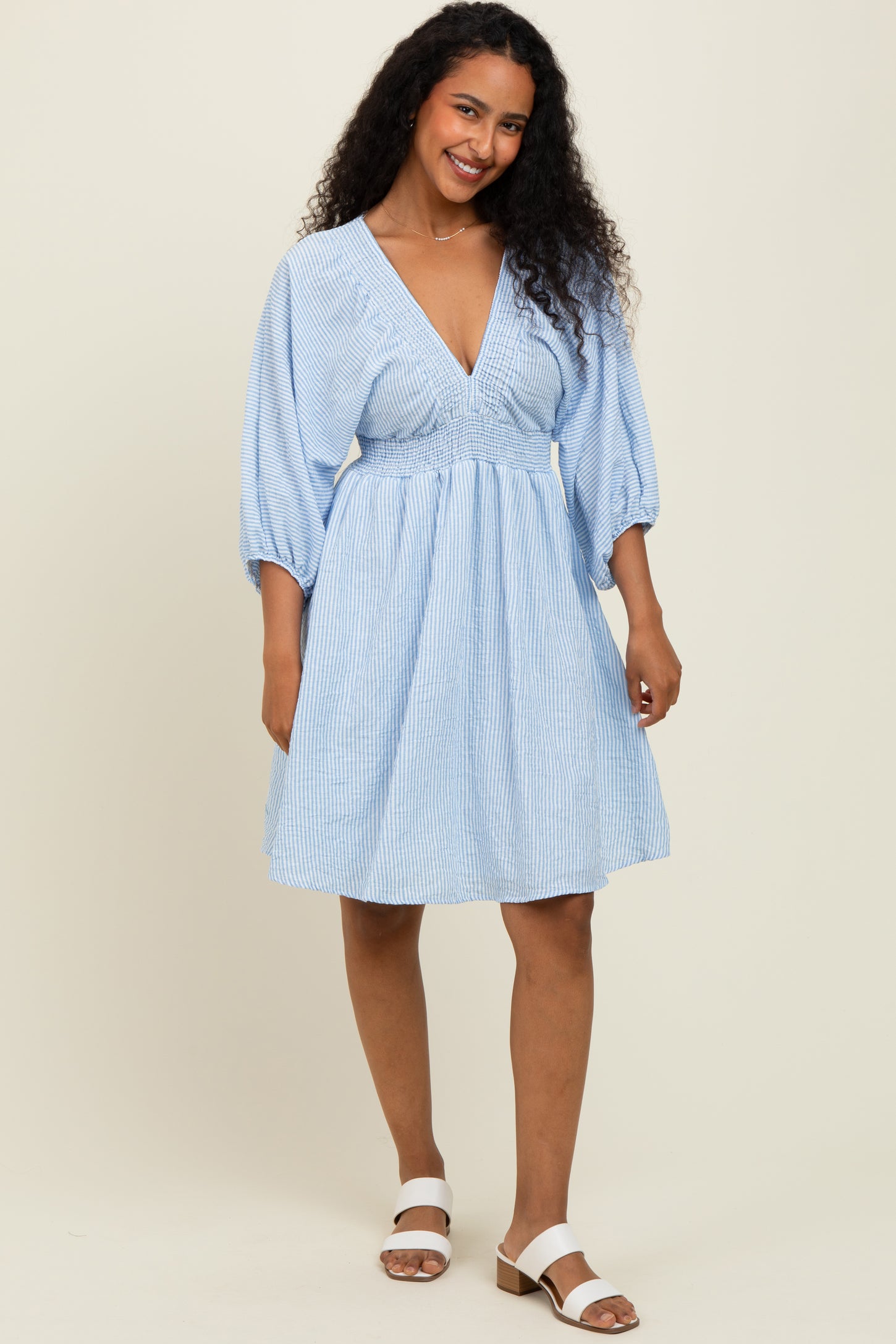 woman wearing a light blue striped short sleeve dress with a deep v-neckline and a cinched waist
