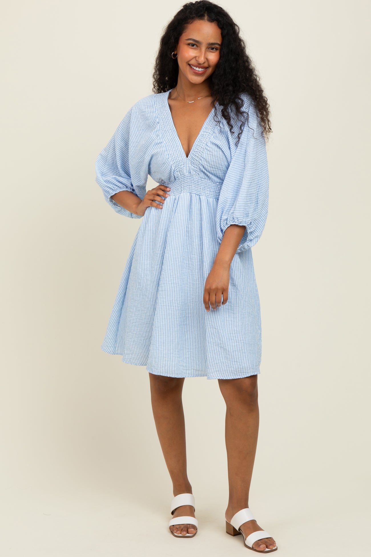 woman wearing a light blue striped short sleeve dress with a deep v-neck and puff sleeves
