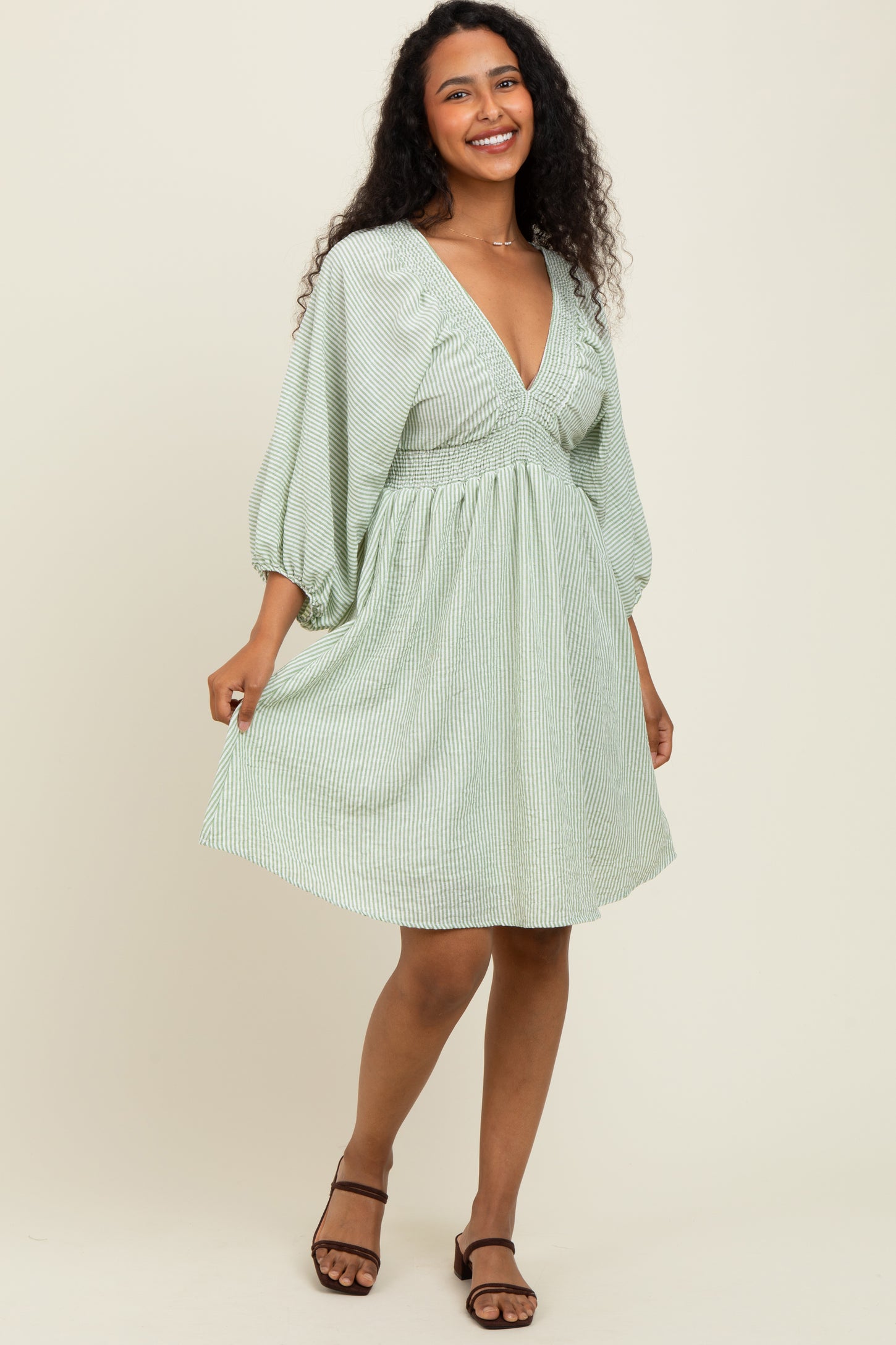 woman wearing a green and white striped short puff sleeve dress with a v-neckline and a flared skirt