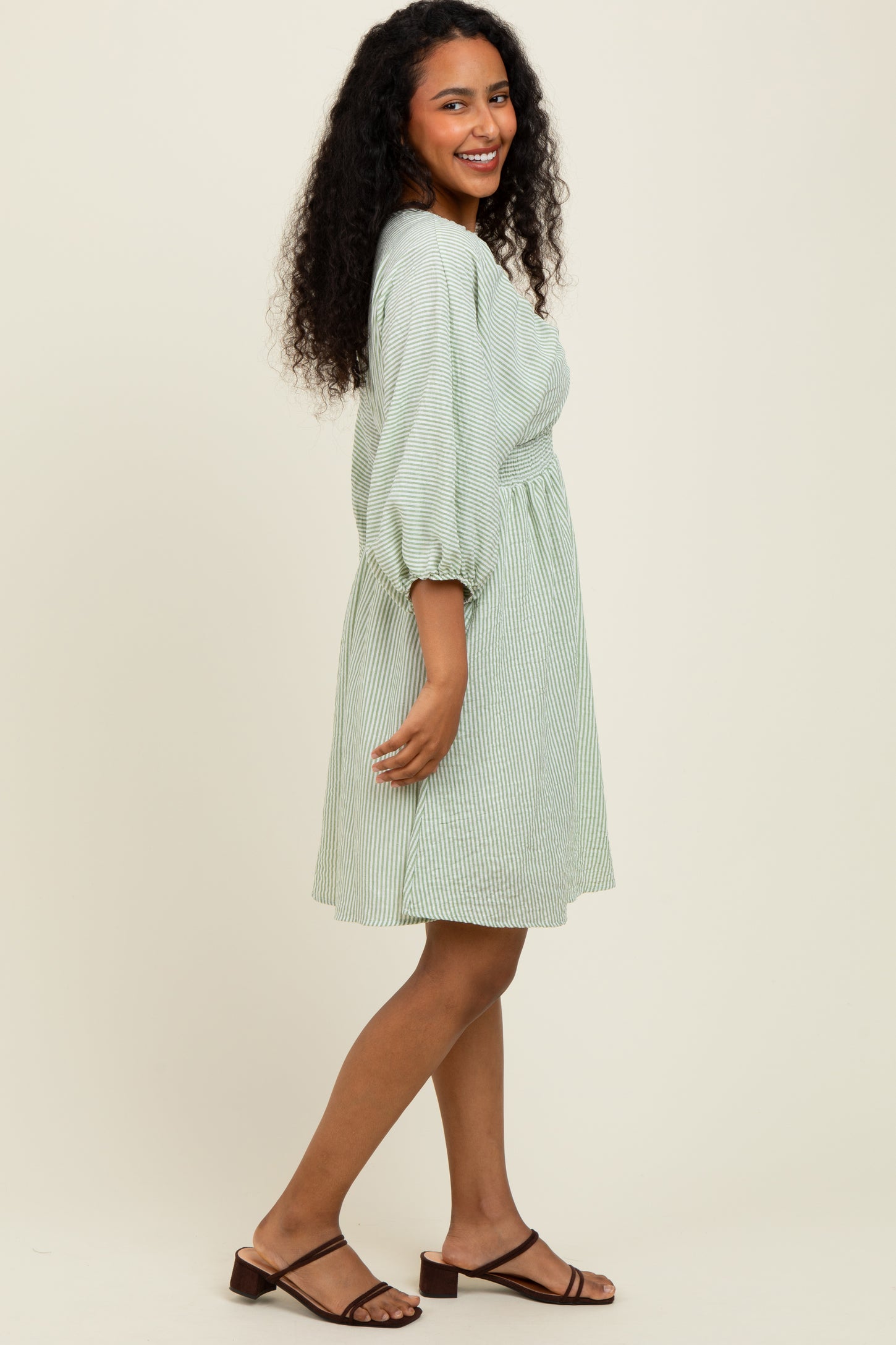 woman wearing a green and white striped short sleeve dress with a cinched waist and puff sleeves