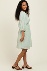 woman wearing a green and white striped short sleeve dress with a cinched waist and puff sleeves