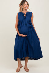 woman wearing a navy blue sleeveless maternity dress with pleats and a tie detail, showing off her baby bump