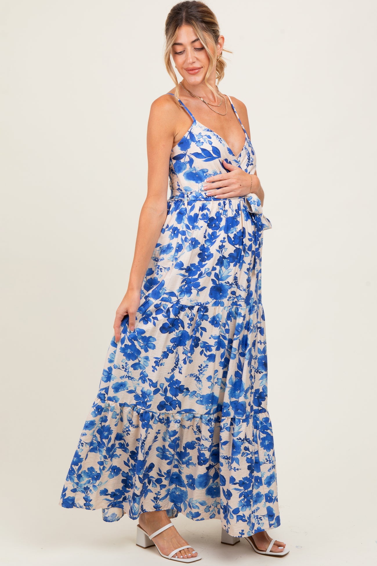 woman wearing a floral blue maternity maxi dress with spaghetti straps and tiered hem, highlighting her baby bump