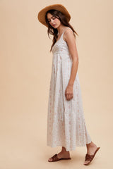 woman wearing a light beige floral maxi dress and a wide-brimmed straw hat, standing in profile
