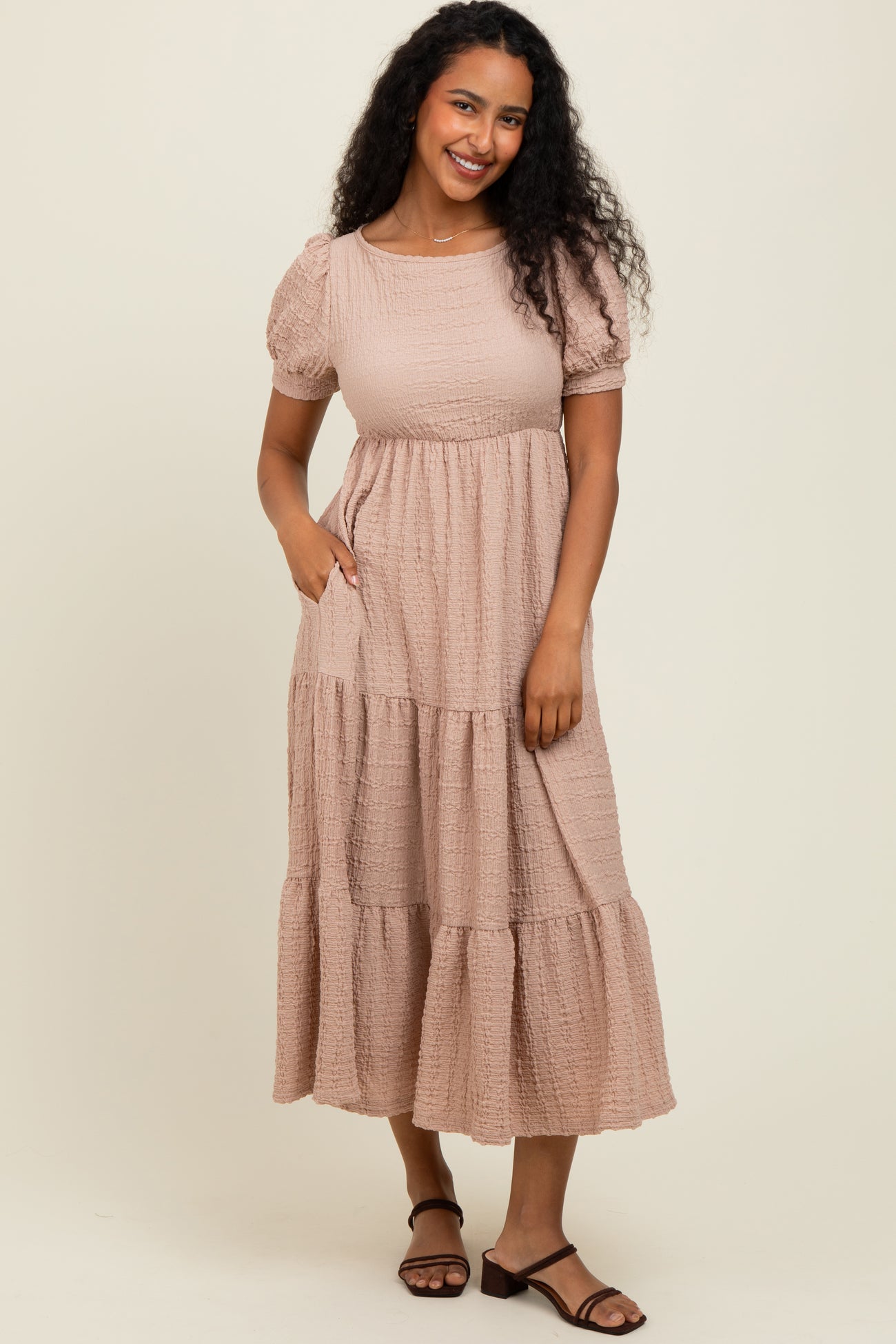 woman wearing a taupe puff sleeve tiered maxi dress with pockets and a relaxed fit
