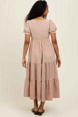 woman wearing a light beige tiered maxi dress with puff sleeves, shown from the back