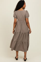 woman wearing a taupe tiered maxi dress with short puff sleeves, viewed from the back