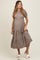 woman wearing a taupe tiered maternity dress with short puff sleeves and a visible baby bump
