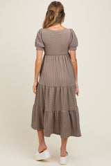woman wearing a taupe tiered maternity dress with short puff sleeves and a comfortable fit