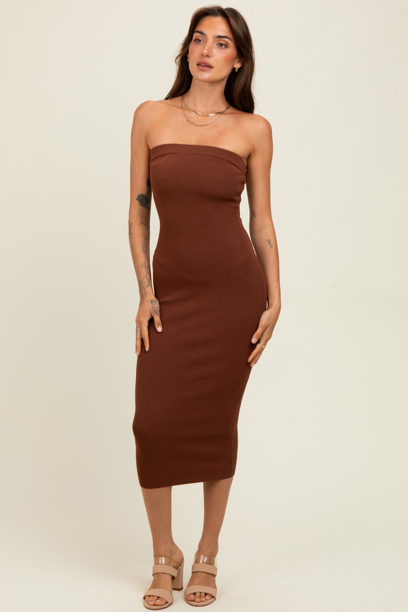 woman wearing a fitted brown strapless midi dress with a ribbed texture and strappy nude heels