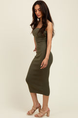 woman wearing an olive green fitted midi dress with a strapless design and styled with beige heeled sandals