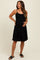 woman wearing a black maternity dress with adjustable straps and a flared skirt, holding her baby bump