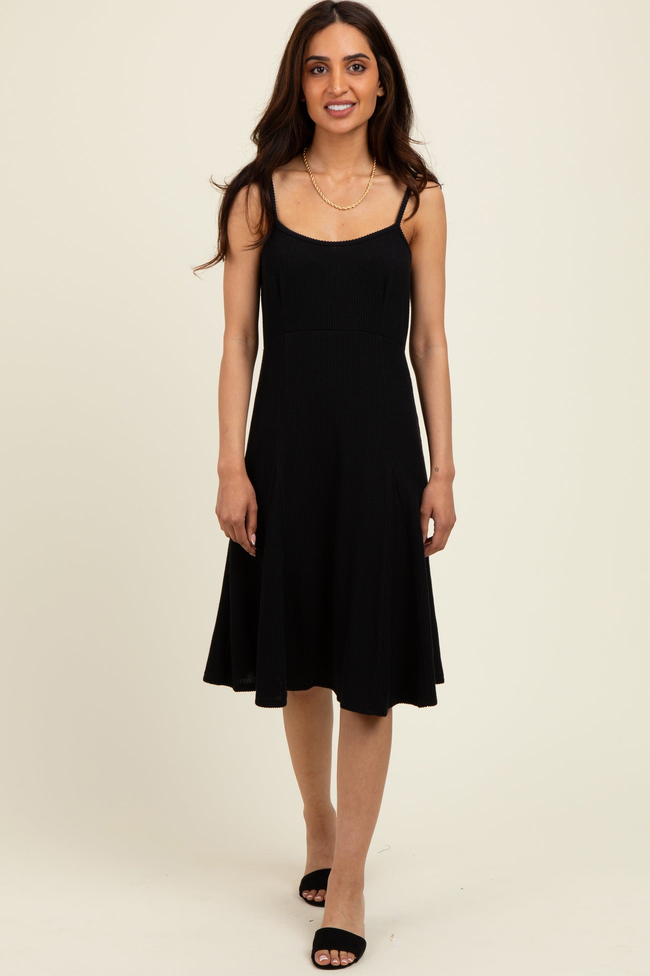 woman wearing a black spaghetti strap fit and flare dress with a ribbed texture