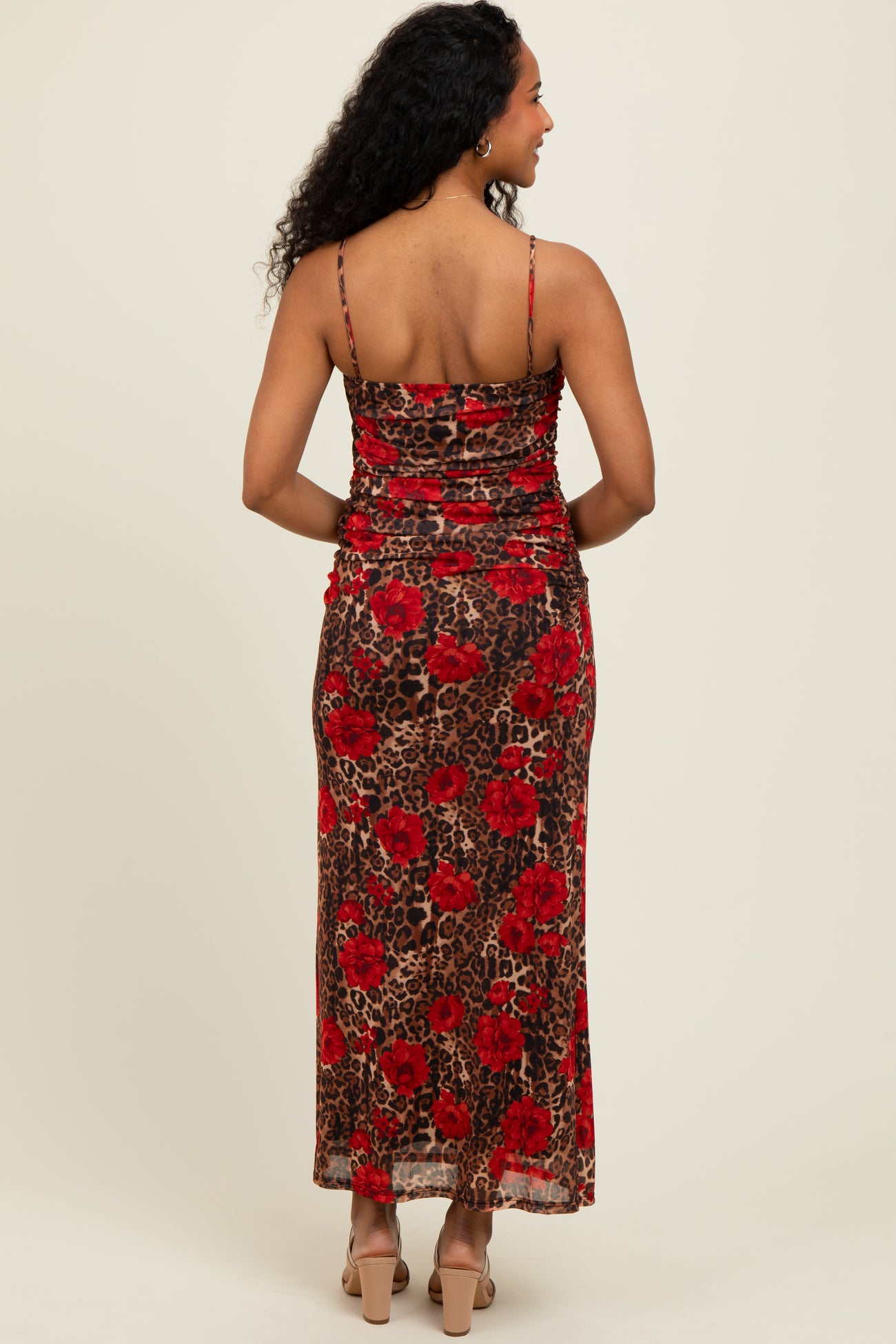 woman wearing a back view of a brown leopard print maxi dress with red floral design and thin spaghetti straps