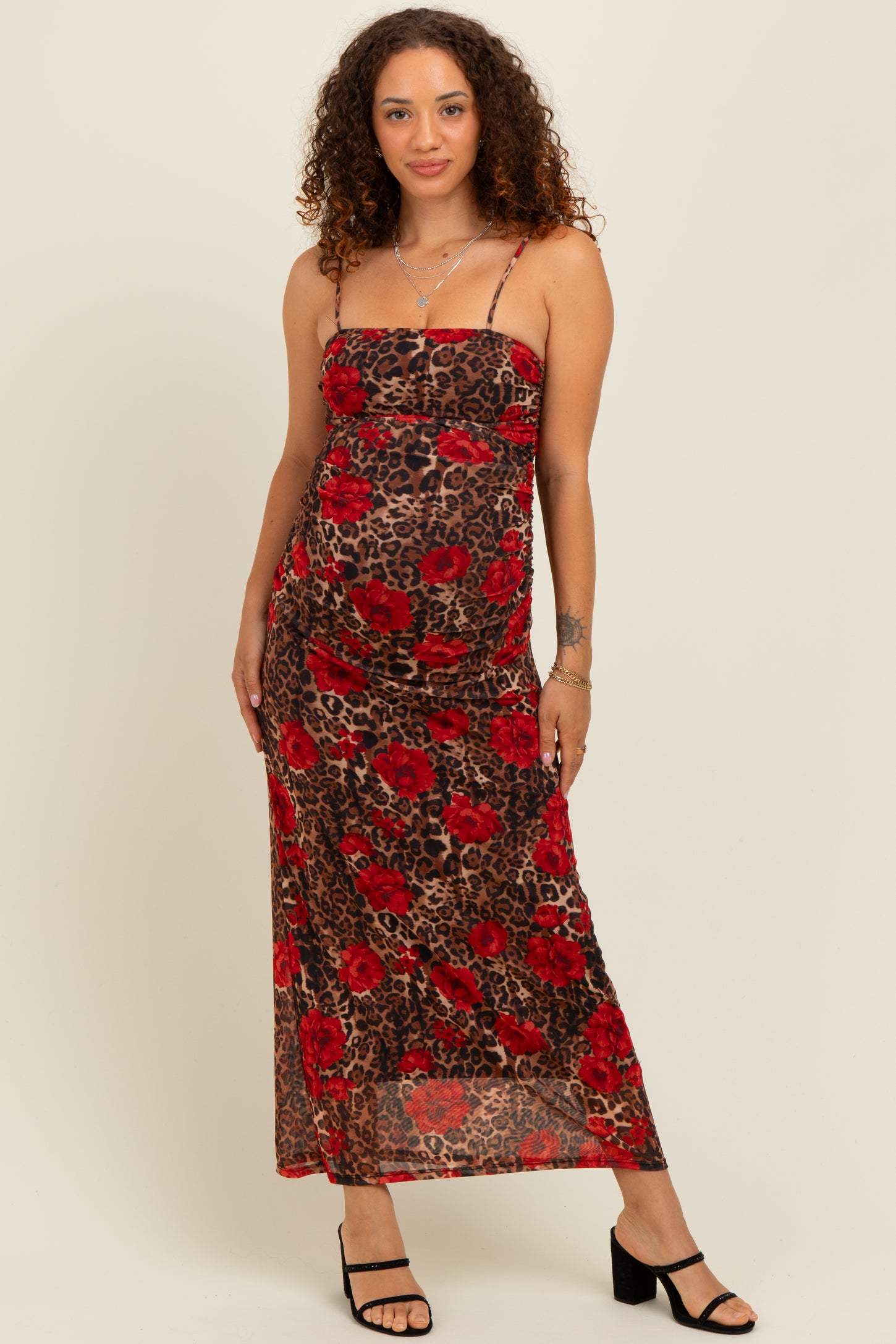 woman wearing a leopard print maternity dress with red floral design and spaghetti straps, showcasing her baby bump