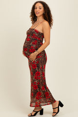 woman wearing a red floral and animal print maternity dress, showing baby bump while holding it with one hand