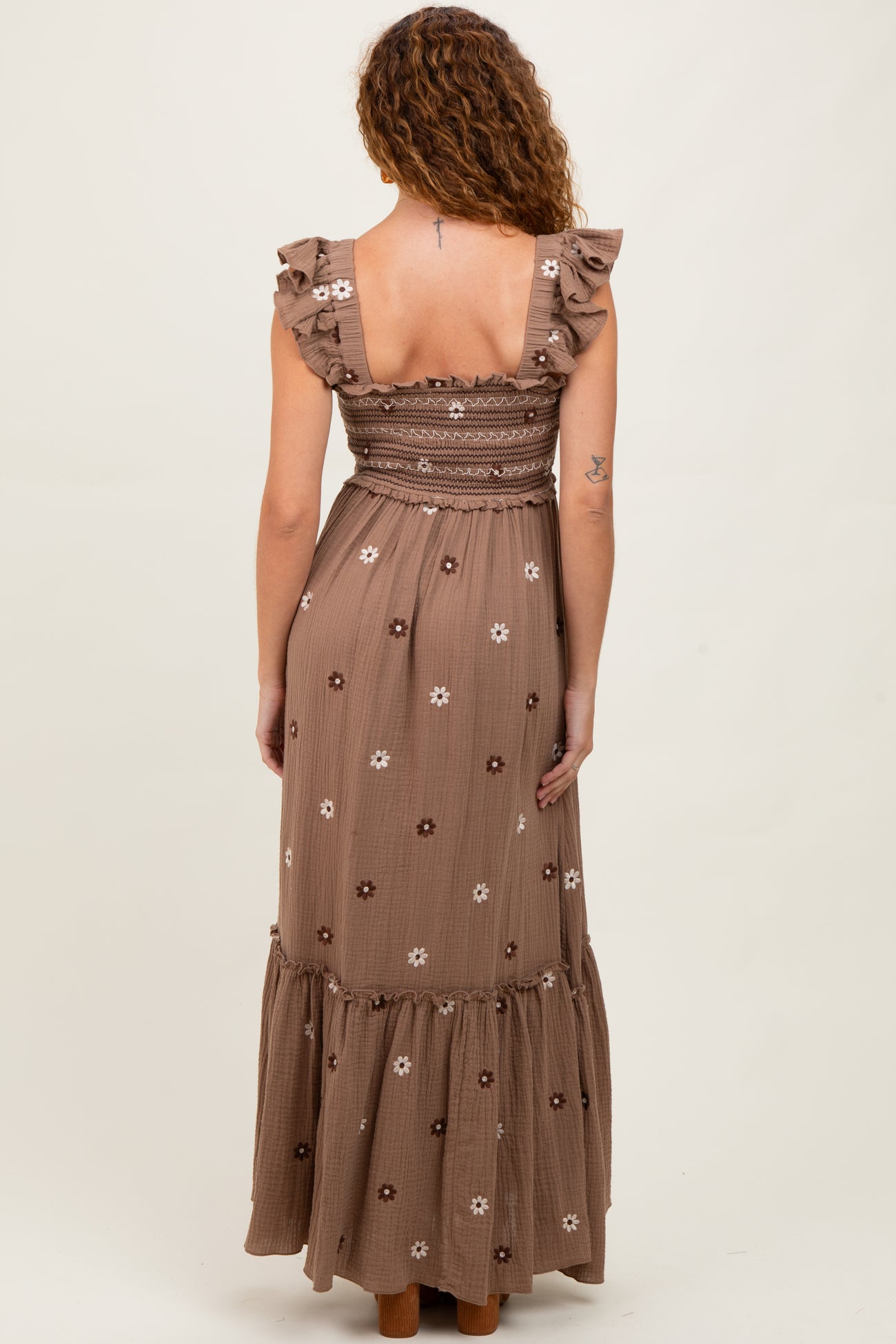 woman wearing a brown floral maxi dress with ruffle straps and a smocked bodice, shown from the back