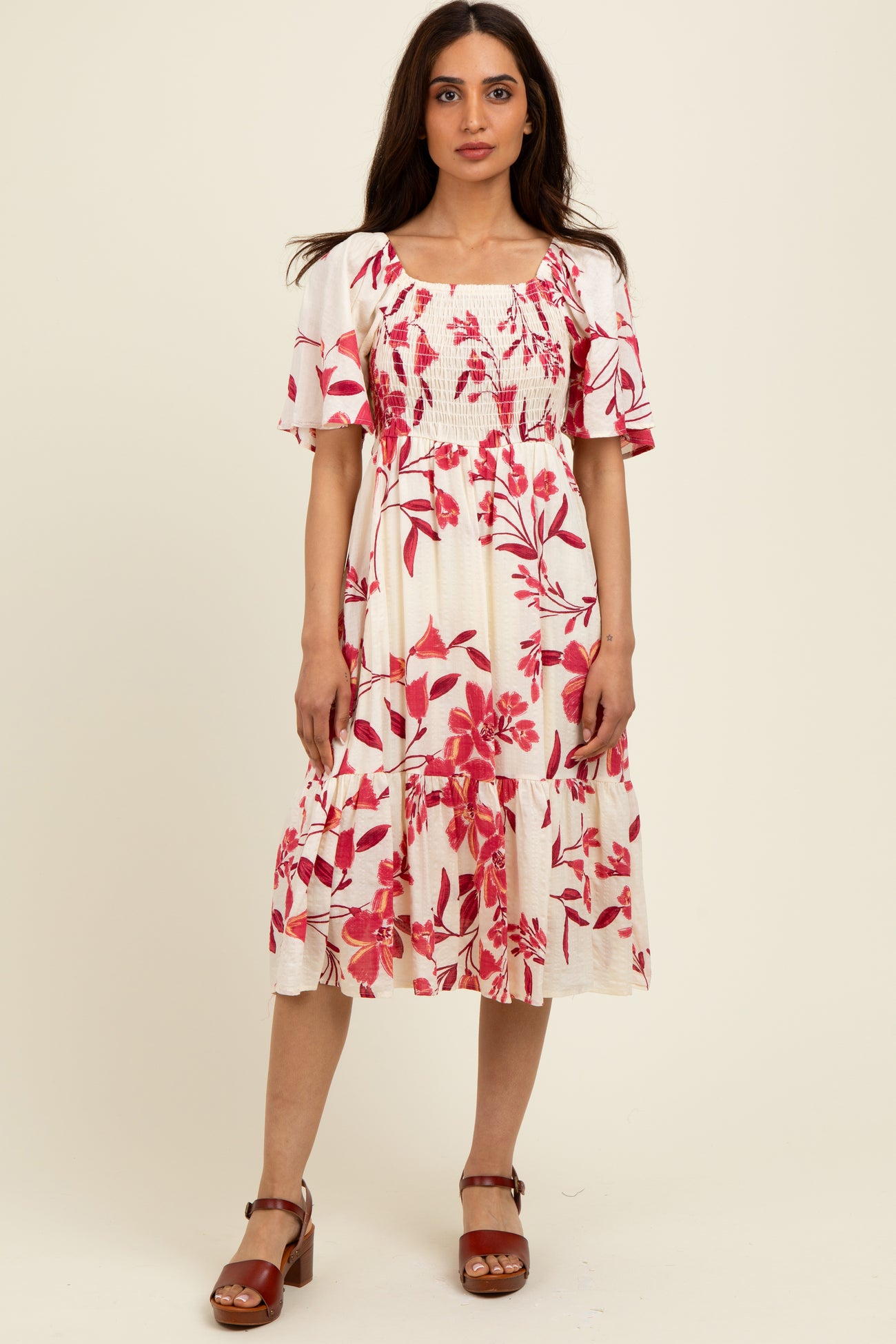 woman wearing a white floral midi dress with red flowers and short sleeves, paired with brown block-heeled sandals