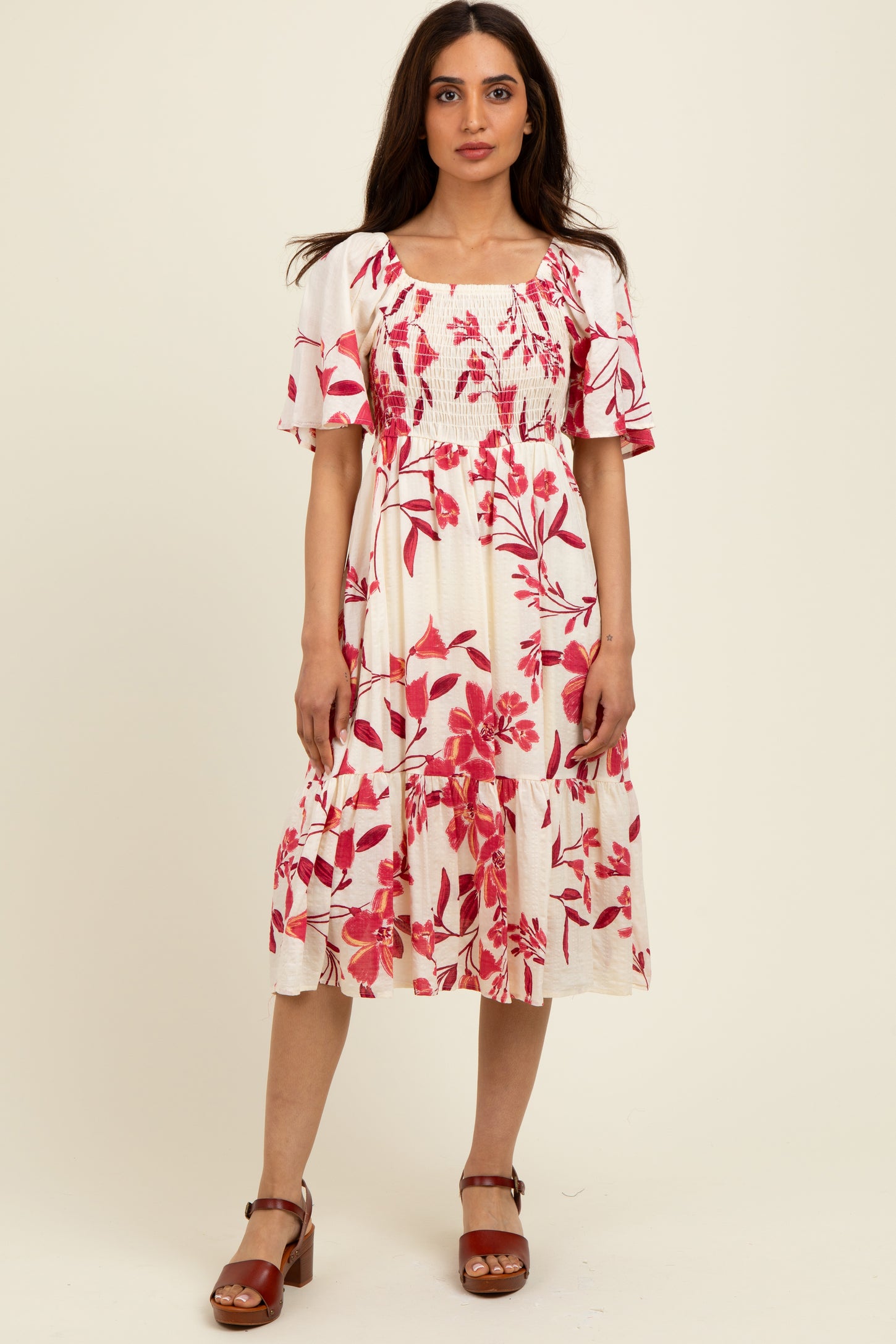 woman wearing a white floral midi dress with red flowers and short sleeves, paired with brown block-heeled sandals