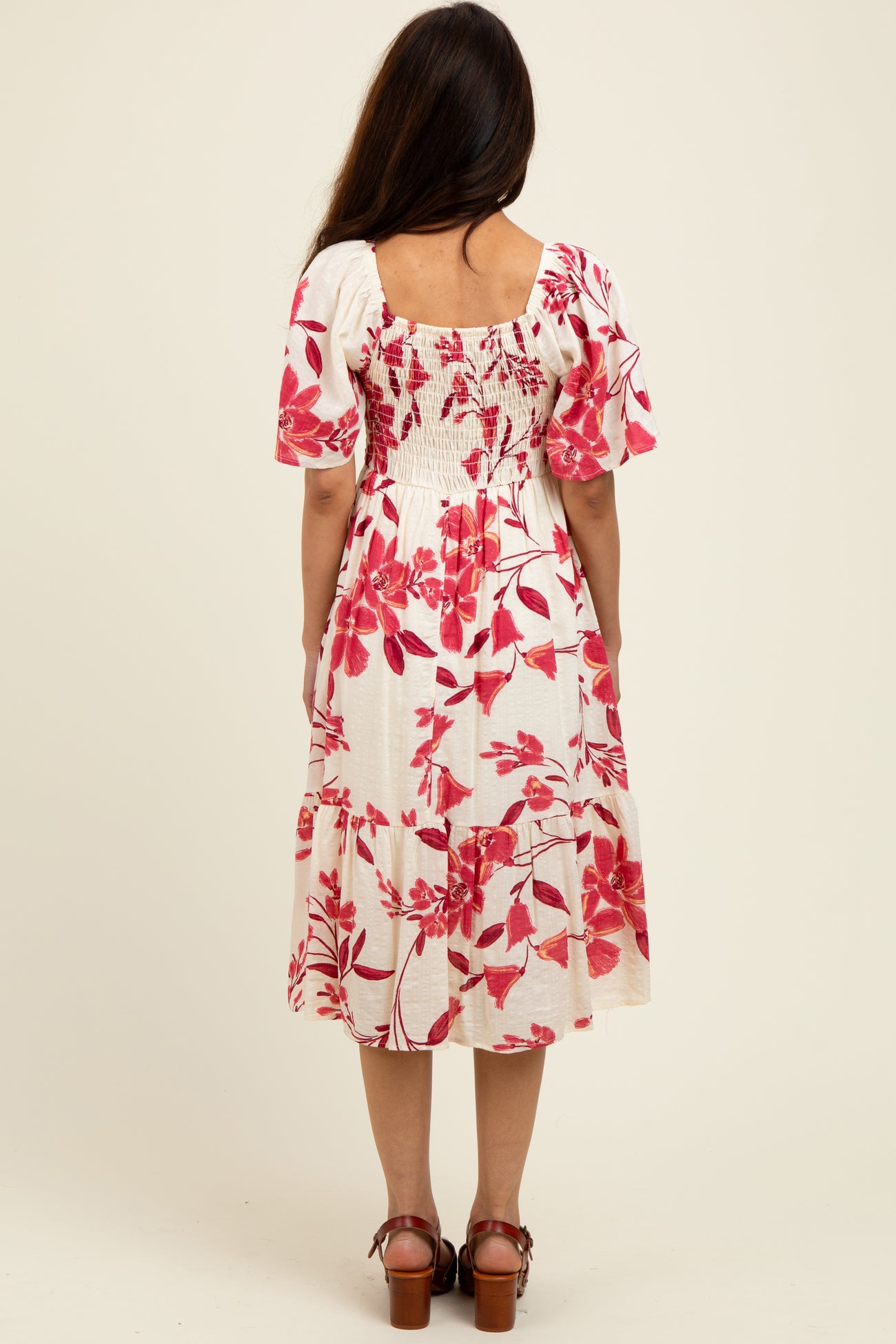 woman wearing a white floral midi dress with pink flowers and puff sleeves, showing the back view