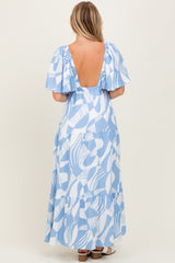 woman wearing a blue leaf print maxi dress with puff sleeves and a deep back neckline
