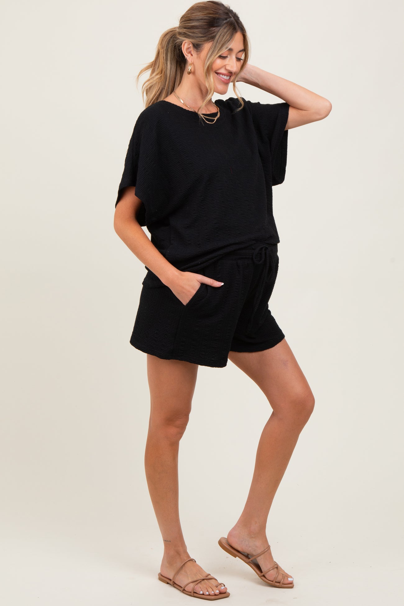woman wearing a black maternity short set with a loose top and shorts, showing her baby bump