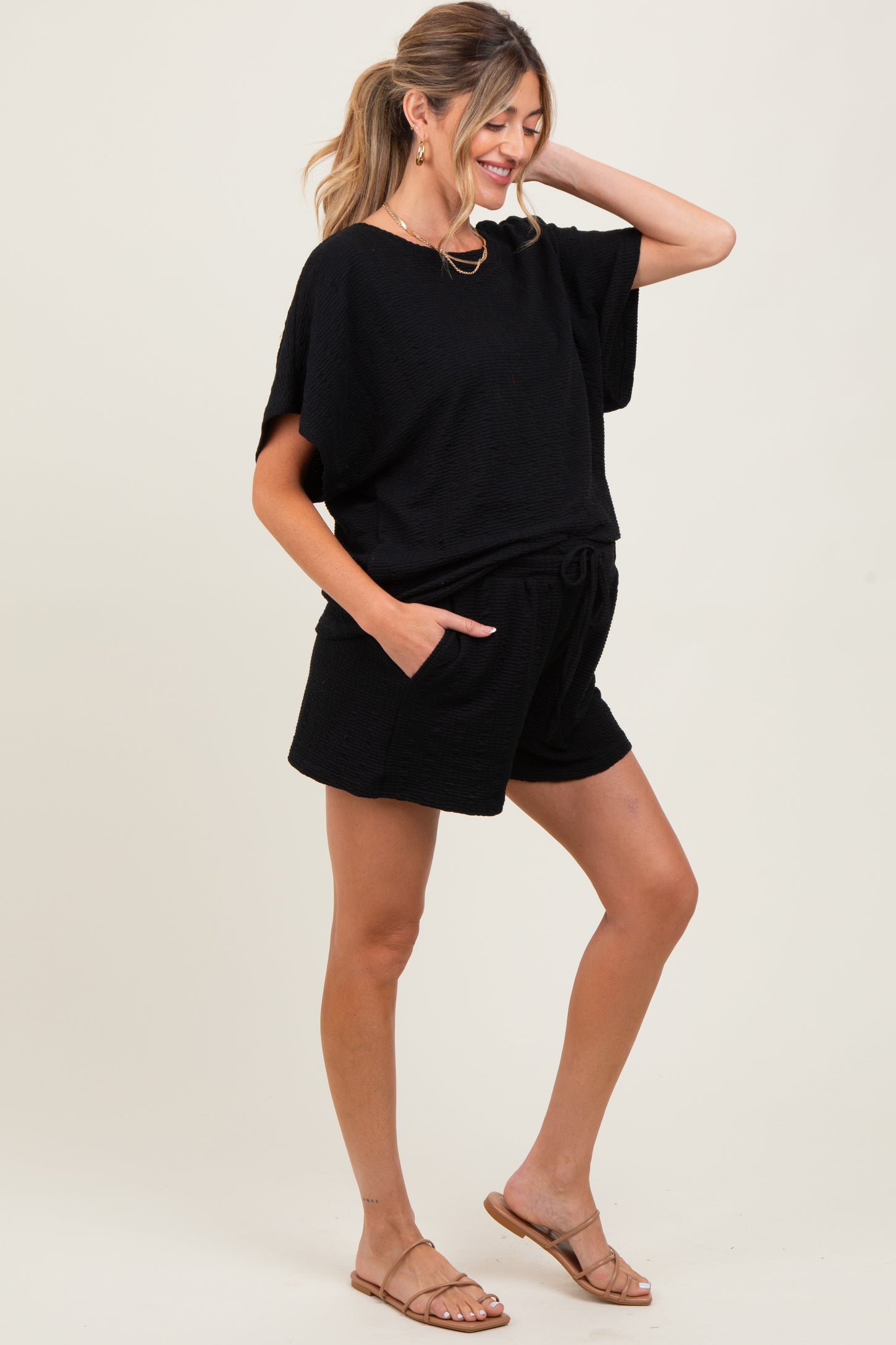 woman wearing a black maternity short set with a loose top and shorts, showing her baby bump