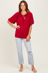 woman wearing a red blouse with a tie neckline and puff sleeves, paired with distressed light blue jeans