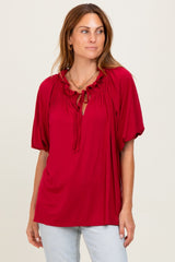 woman wearing a red short sleeve blouse with ruffle details and a keyhole tie neckline