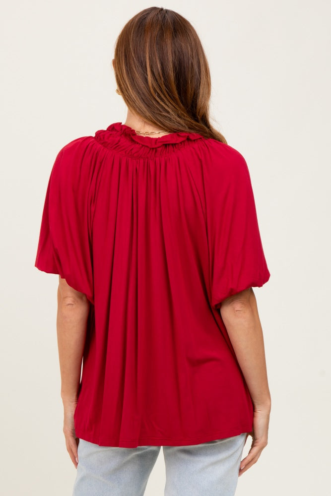woman wearing a red short sleeve blouse with gathered neckline and loose fit, view from the back