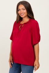 woman wearing a red maternity top with gathered neckline and puff sleeves, showing her baby bump