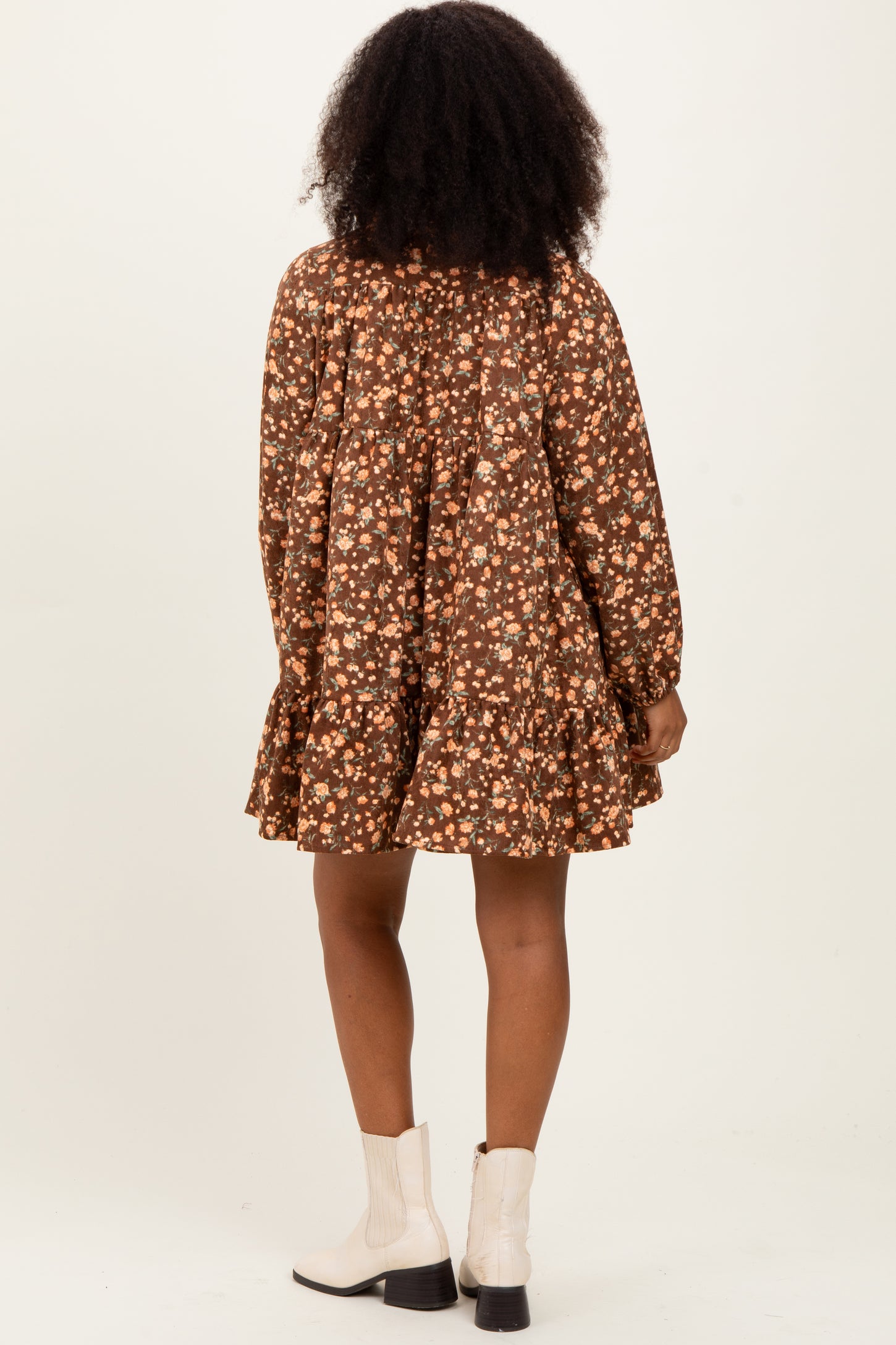 woman wearing a brown floral long sleeve dress with a tiered hem and a flared silhouette, seen from the back