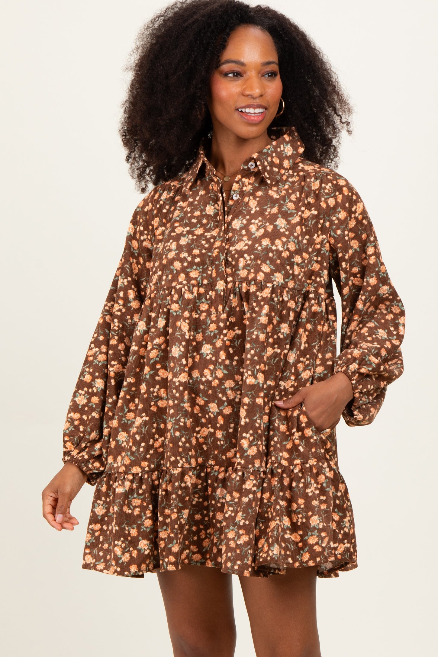 woman wearing a brown floral print long sleeve dress with a tiered skirt and pockets