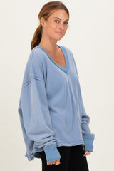 woman wearing a soft blue oversized v-neck sweatshirt with rolled sleeves and a relaxed fit