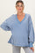 woman wearing a blue oversized v-neck maternity sweatshirt with stitching details and relaxed sleeves