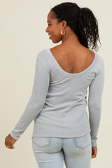 woman wearing a light gray ribbed long sleeve top with a wide scoop back and styled with light blue jeans