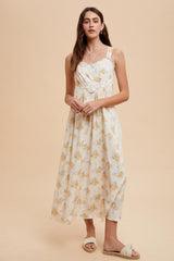 woman wearing a cream floral maxi dress with adjustable straps and a gathered waist, styled with sandals