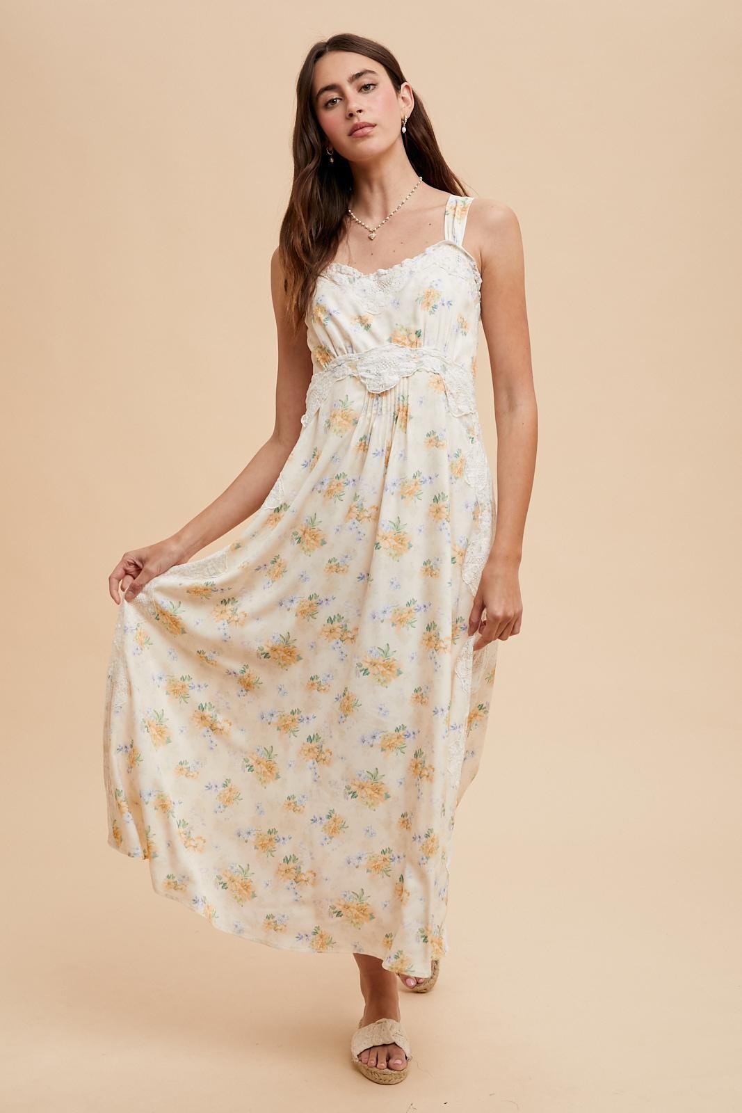 woman wearing a floral maxi dress with adjustable straps and a fitted bodice, posing against a neutral background