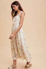 woman wearing a floral print maxi dress with lace detailing and braided straps, styled with casual footwear