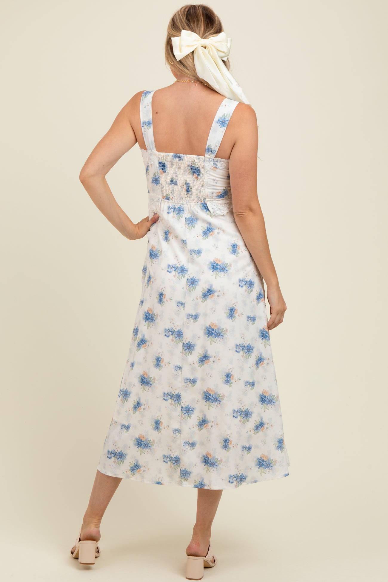 woman wearing a floral print maternity dress with a smocked back and adjustable straps, facing away from the camera