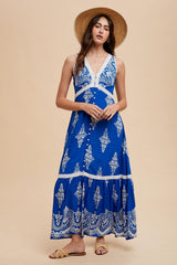 woman wearing a blue bohemian maxi dress with embroidered details and buttons, paired with a straw hat