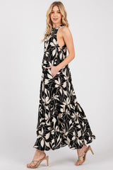 woman wearing a black and cream floral maxi dress with a ruffled hem and pockets