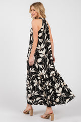 woman wearing a floral black and white maxi dress with a tiered skirt and open back, posing from the side