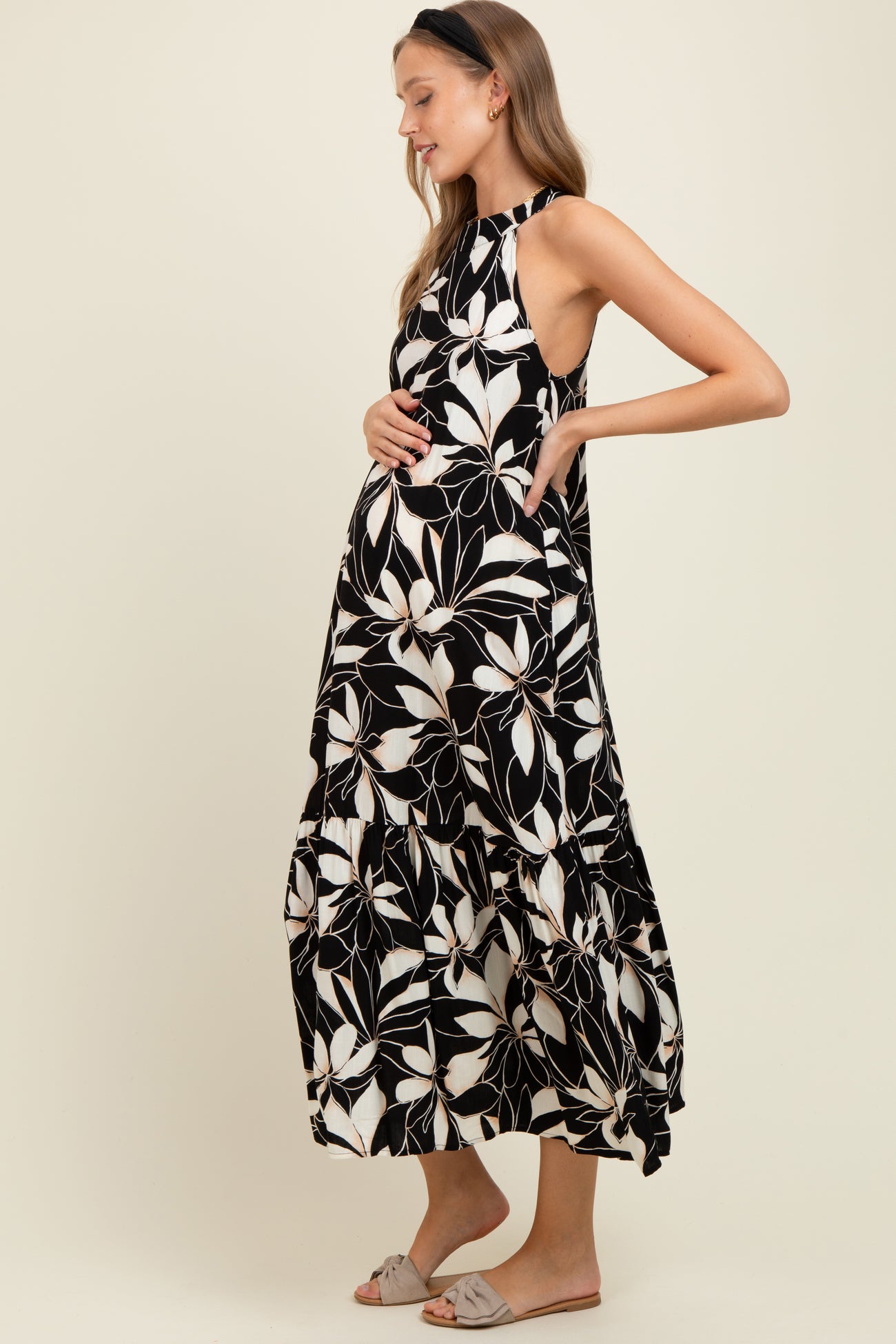 woman wearing a black and white floral maternity maxi dress and holding her baby bump